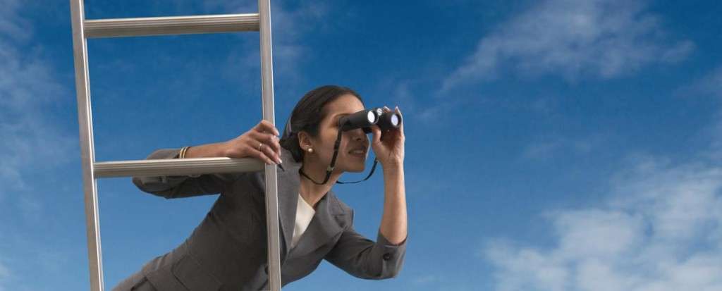 Businesswoman standing on a ladder looking through binoculars --- Image by © Royalty-Free/Corbis